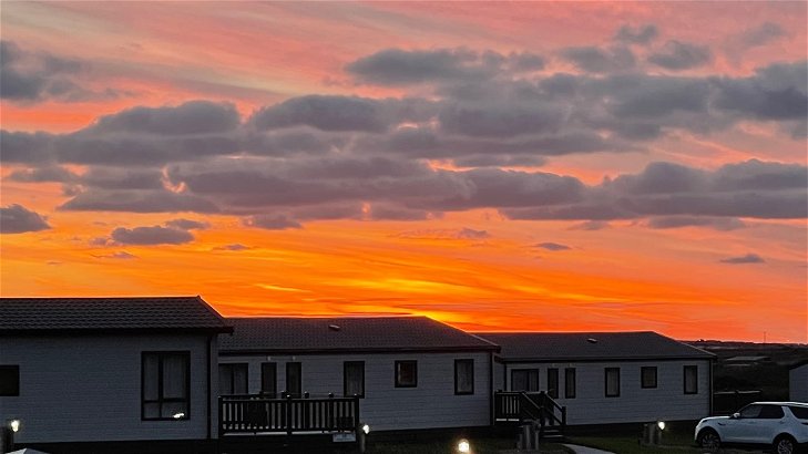 A fiery orange sunset over the lodges at Newperran
